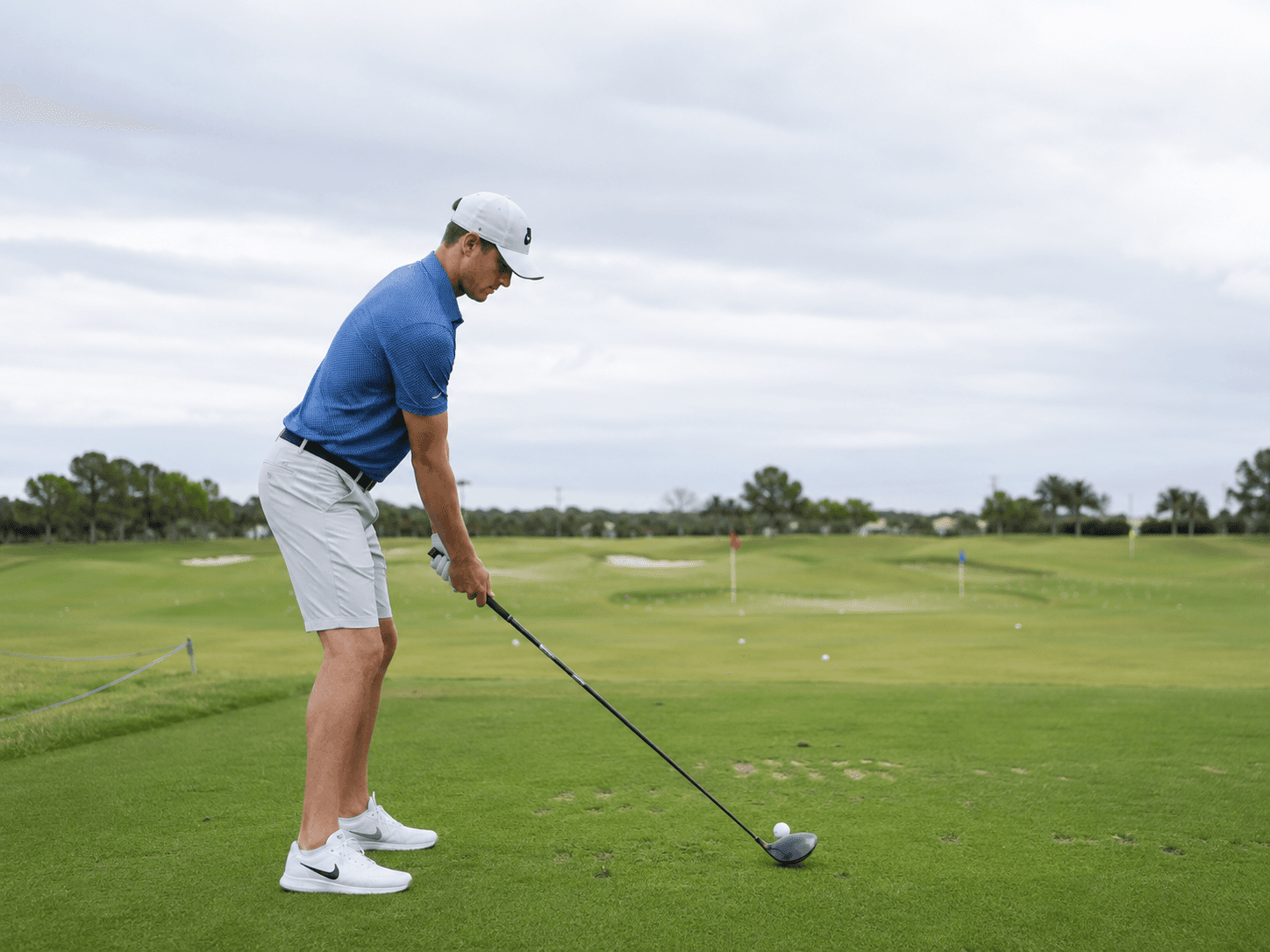 Golfer addressing the ball with the full club visible on a practice range